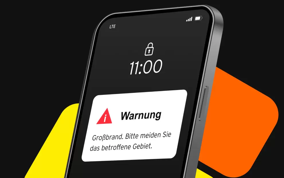 Beispielabbildung von einem Smartphone mit Sperrbildschirm, das folgende Warnmeldung zeigt: "Warnung! Großbrand. Bitte meiden Sie das betroffene Gebiet."
